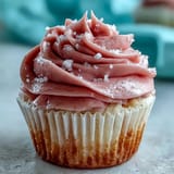 Freshly baked Pink Velvet Cupcakes are topped with piped vanilla buttercream and a sprinkle of pink sanding sugar.