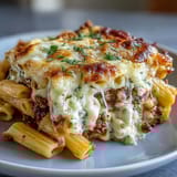 Cottage Cheese Protein Pasta Bake with ground beef served in a white dish, topped with fresh parsley and a rustic wooden spoon nearby.