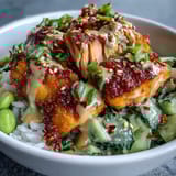 Bang Bang Salmon Bowl topped with toasted sesame seeds and fresh cilantro, served with lime wedges for a bright squeeze.