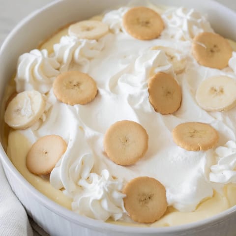 A layered view of creamy, sweet banana pudding, boasting banana slices and vanilla wafers.