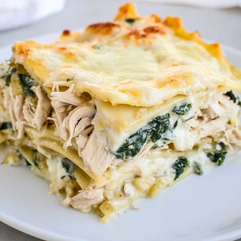Golden mozzarella blankets this hearty Chicken Alfredo Lasagna, served hot from the oven in a ceramic dish.
