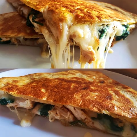 A freshly grilled Chicken and Spinach Quesadilla cut into wedges, with sour cream and salsa on the side.  
