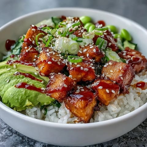 Freshly baked marinated salmon cubes rest on fluffy jasmine rice with vibrant edamame and avocado slices in this Salmon Rice Bowl.