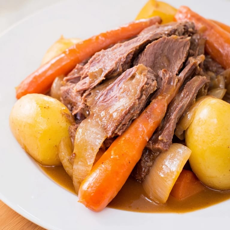 A bubbling Dutch oven reveals the savory Beef Pot Roast with soft vegetables and a deep, delicious sauce.