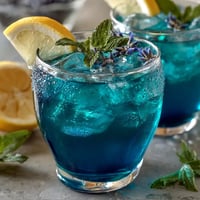 Close-up of vibrant Butterfly Pea Flower Lemonade, its blue tea swirling into pink.
